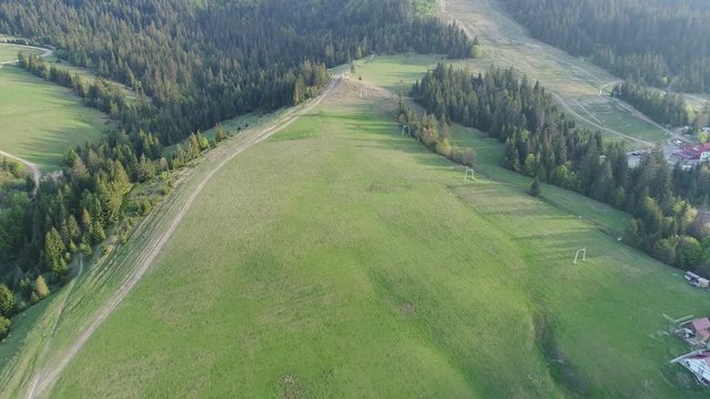 Flying over the beautiful Ukrainian Carpathians mountain and coniferous forest overlooking the beautiful lush green valley and the village. Aerial camera shot. Landscape panorama. Ukraine