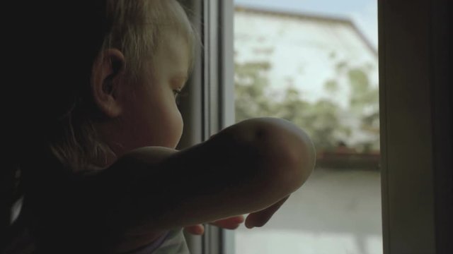 Mother is standing with a small child in front of a window in silhouette