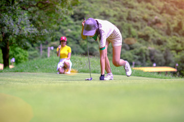 legs of woman golf player step-in to takes golf ball from the hole on the green, golfmate...