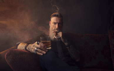 Portrait eines attraktiven Geschäftsmannes mit einer Zigarre und einem Glas Whisky in einem...