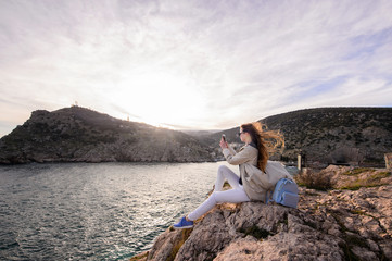Beautiful girl outdoors. Spring day. The girl with long hair photographes itself near the sea