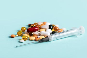 Pills and and syringe on blue background