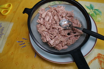 Preparing tuna fish for lunch dish in a colander 