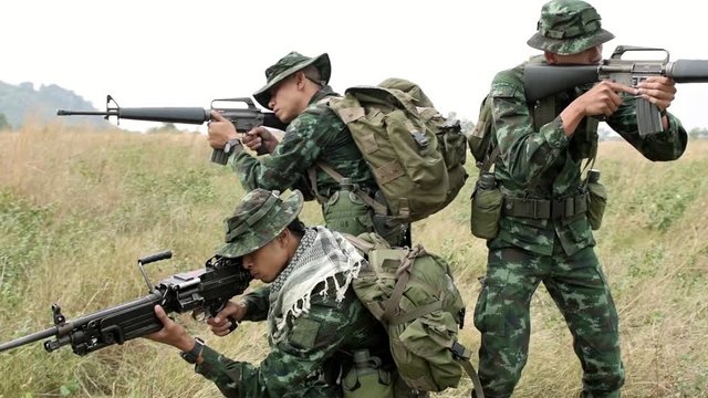 Slow motion of soldiers aiming their assault rifles on grass. Chinese soldiers on grass land aiming their weapon standing up, special forces training. Ready to assault terrorist.