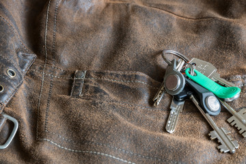 Naklejka premium A bunch of keys on an old denim worn brown jacket. Worn texture of jeans. A pocket with a rivet. Pattern, design.