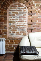 Fototapeta na wymiar Part of the white sofa on the background of the red brick wall of the ancient house. The concept of fashion and style