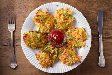 Potato Zucchini and Carrot Cakes. Vegetable fritters, latkes, draniki. Vegetable pancakes on white plate on wooden table. overhead, horizontal