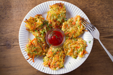 Potato Zucchini and Carrot Cakes. Vegetable fritters, latkes, draniki. Vegetable pancakes on white plate on wooden table. overhead, horizontal