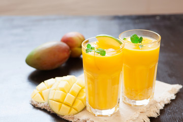 Fresh mango smoothie in glass with fruits on the wooden table