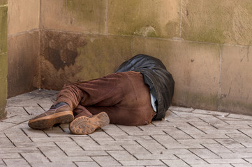 Obdachloser schläft an einer Sandsteinmauer