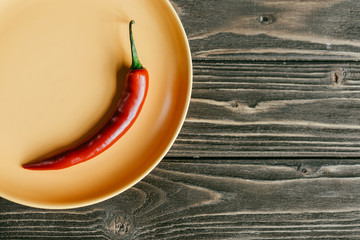 Red hot pepper served on plate on wooden table