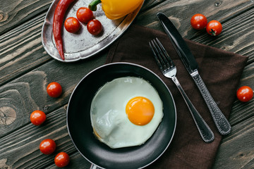 Clean eating concept with fried egg and raw vegetables on wooden table