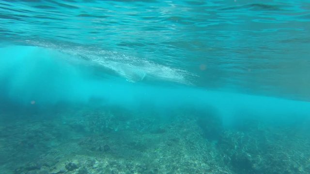 SLOW MOTION, UNDERWATER: Unrecognizable pro rider carving a stunning glassy wave during perfect summer holiday in Fiji. Awesome surfer making sharp turns on his surfboard while riding a breaking wave.