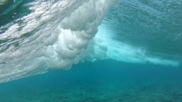 SLOW MOTION, UNDERWATER: Spectacular barrel wave rushes from the open seas of the Pacific ocean and toward the tropical shore. Beautiful shiny emerald tube wave rolls over the tropical reef near Fiji.