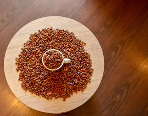 A coffee cup with coffee beans is on a light round table