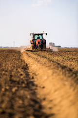 Fototapeta premium Farmer in tractor preparing land with seedbed cultivator as part of pre seeding activities in early spring season of agricultural works at farmlands.
