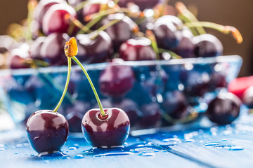 Ripe sweet cherries on blue woden table with water drops