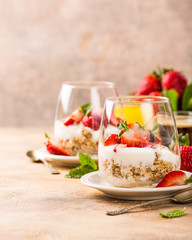 Healthy breakfast with oatmeal granola, strawberries and yogurt on light brown background. Copy space.
