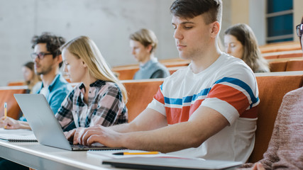 Handsome Caucasian Student Uses Laptop while Listening to a Lecture at the University. Multi Ethnic Group of Modern Bright Students Invested in Their Future.