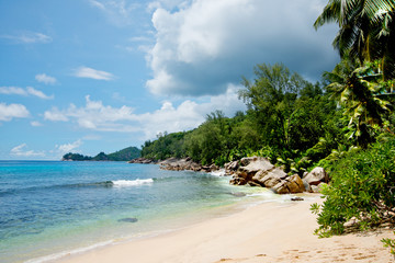 Beautiful view of the Indian Ocean from the island of Mae, Seychelles.  On the ocean lie huge stones.  Evergreen vegetation is in the foreground.