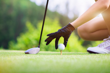golf ball in hand of woman takes on to wooden tee on tee off of the golf course, ready to hit away...