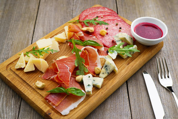 Chef's snacks set, menu photo, luxury restaurant meals. Prosciutto, salami and gourmet cheeses served on board with sauce