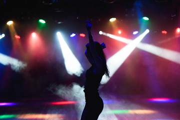 Fototapeta na wymiar Silhouette of dancing girl against disco lights