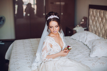 Fototapeta premium Attractive young bride holding the groom's buttonhole. flowers with pink roses, white carnation and green and greens. Bride's Preparations. Wedding Morning.