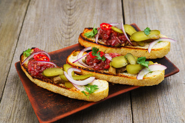 Italian appetizer, gourmet snack, banquet, restaurant menu concept. Delicious pickled gherkin and salmon bruschettas on restaurant table