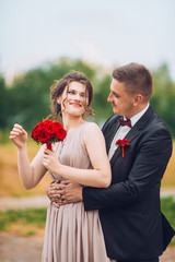 Portrait of a happy couple laughing at camera. Bridesmaid and groomsmen outdoor portrait. Funny...