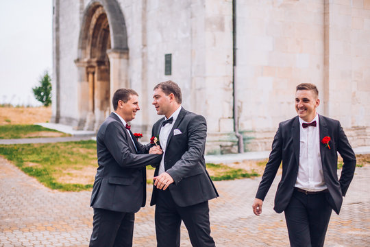 Young groom and his funny friends groomsman posing for camera. Group of young men with bow tie. Cheerful friends. friends outdoors. Wedding day.