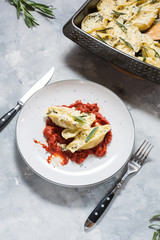 Italian pasta Conchiglioni Rigati stuffed with cheese and greens on concrete table.