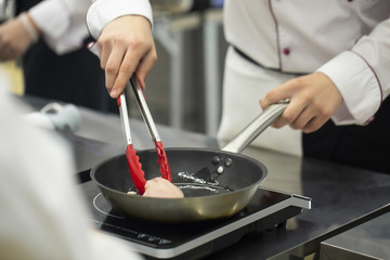 Cook prepares the chicken in a frying pan. Selected focus