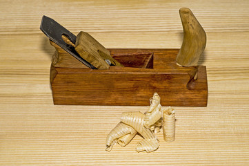 Hand-made wooden plane and wooden shavings on the table close-up. The concept of DIY. Tools for woodworking and crafts.