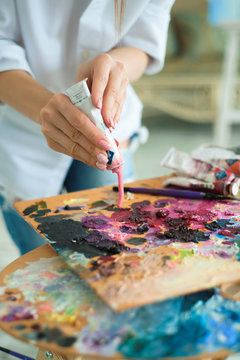 art, creativity and people concept - close up of artist with palette knife painting still life on easel at studio