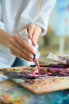 art, creativity and people concept - close up of artist with palette knife painting still life on easel at studio