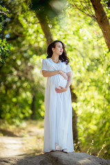 Beautiful pregnant woman with her husband in green garden
