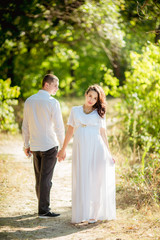 Beautiful pregnant woman with her husband in green garden