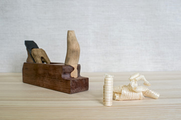 Hand-made wooden plane and wooden shavings on the table close-up. The concept of DIY. Tools for...