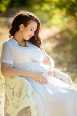 Beautiful pregnant woman with her husband in green garden