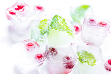 ice cubes with red berries and mint white background