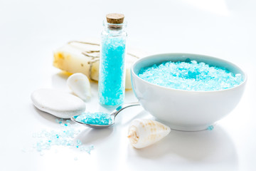 Fototapeta na wymiar blue bath salt, body cream and shells for spa on white table bac