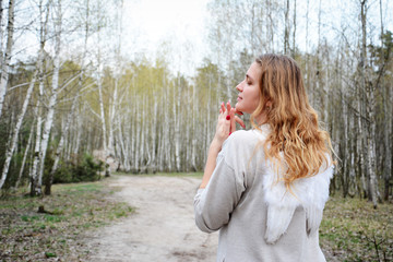 In the spring forest there is an angel girl with white wings.