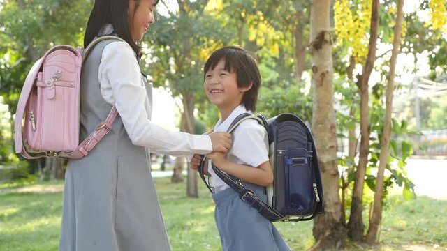 Cute Asian children going to the school outdoors 