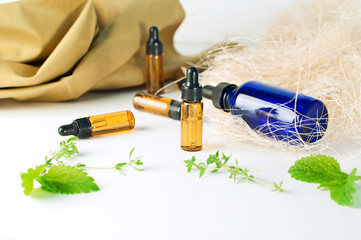 Brown and blue bottles of essential oil with fresh mint and thyme