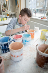 Boy painting pottery cup 