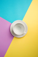 white empty coffee Cup on bright yellow-turquoise-purple background. copy spase, flat lay