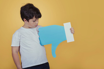 niño triste con un dislike grande sobre fondo amarillo