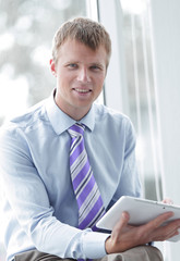 Handsome young man in a blue shirt using a tablet