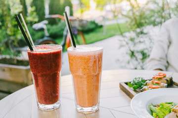 Healthy eating and summer concept. Two glasses of smoothies and snacks on a wooden table of a cafe summer terrace.